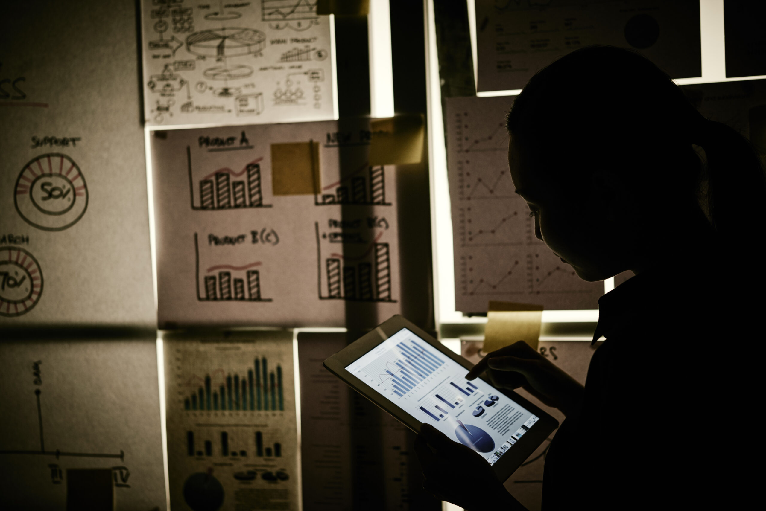 Business lady analyzing chart on tablet computer in dark office